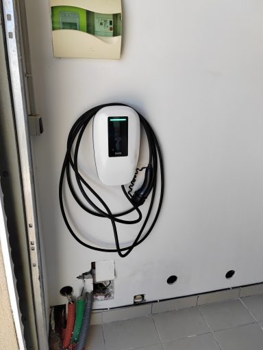 Chargeur de véhicule électrique fixé au mur avec des câbles enroulés.