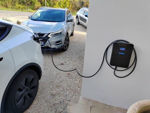 Voiture électrique en cours de charge avec un chargeur mural à proximité.