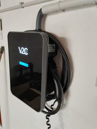 Chargeur de véhicule électrique monté sur un mur, avec câble enroulé.