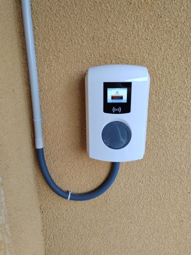 Chargeur de véhicule électrique fixé au mur, avec écran et câbles.