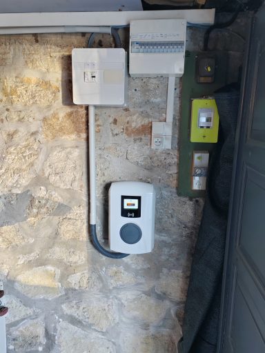 Dispositif d'alimentation électrique sur un mur en pierre avec plusieurs interrupteurs.